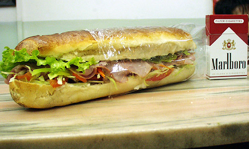 高原野菜タップリのフランスパン・サンドイッチ。とにかくデカイ！タバコの箱とサイズを比べてみてください